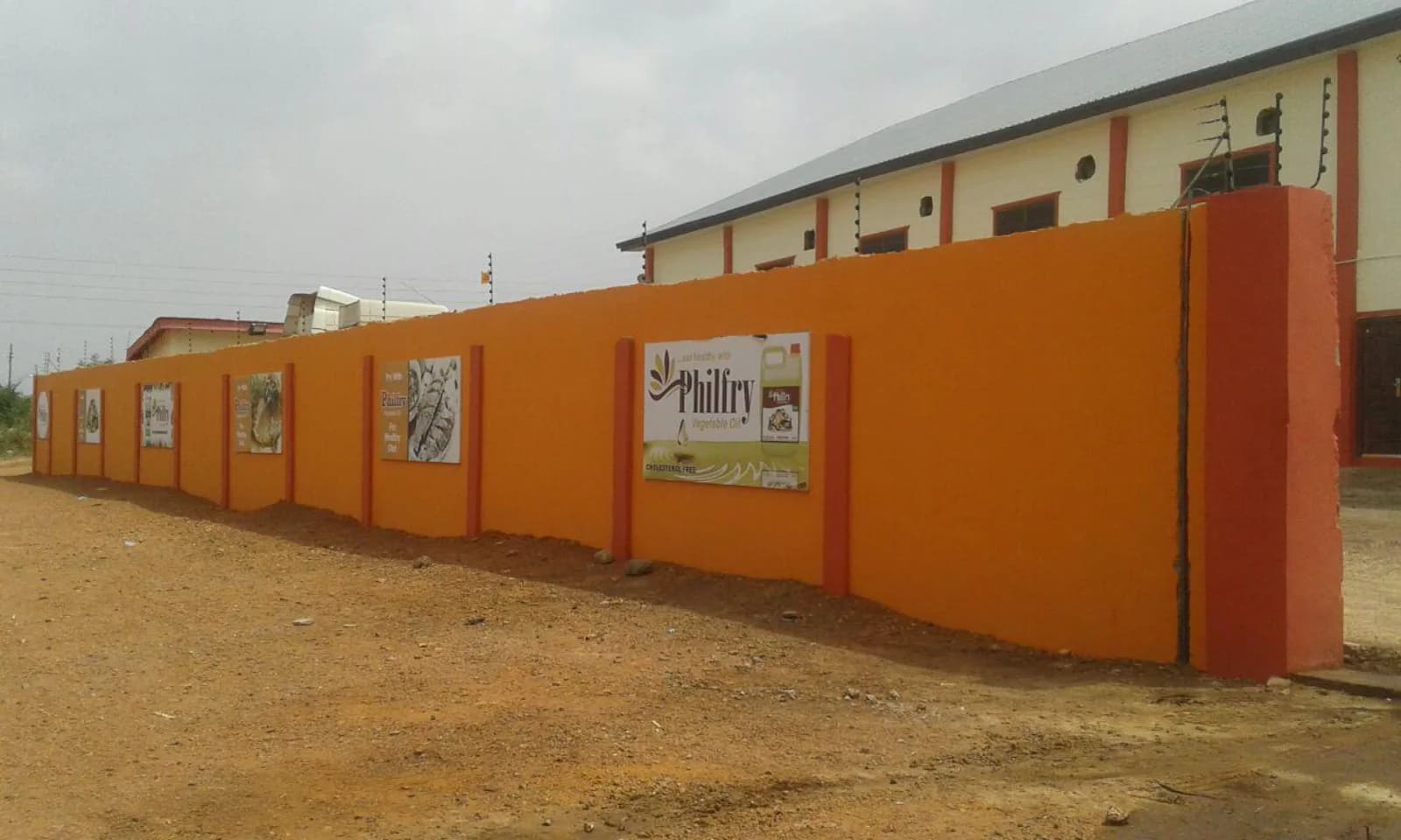 Orange perimeter wall of the Oyarifa factory carrying Philfry branding
