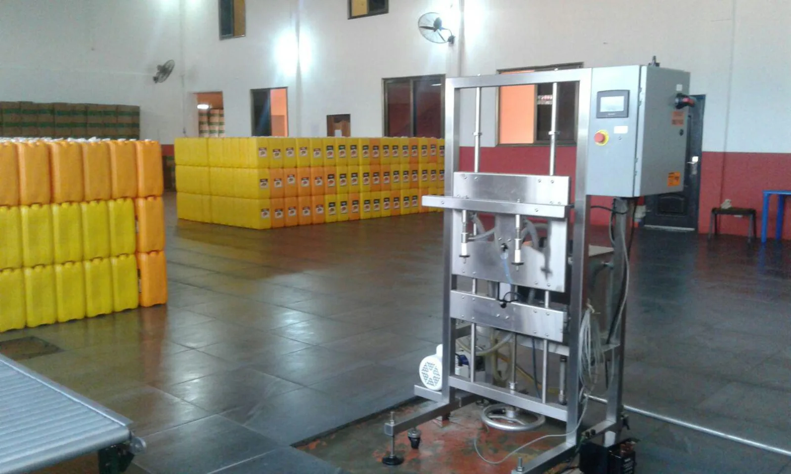 Stainless-steel filling machine beside stacks of yellow Philfry oil jerry cans